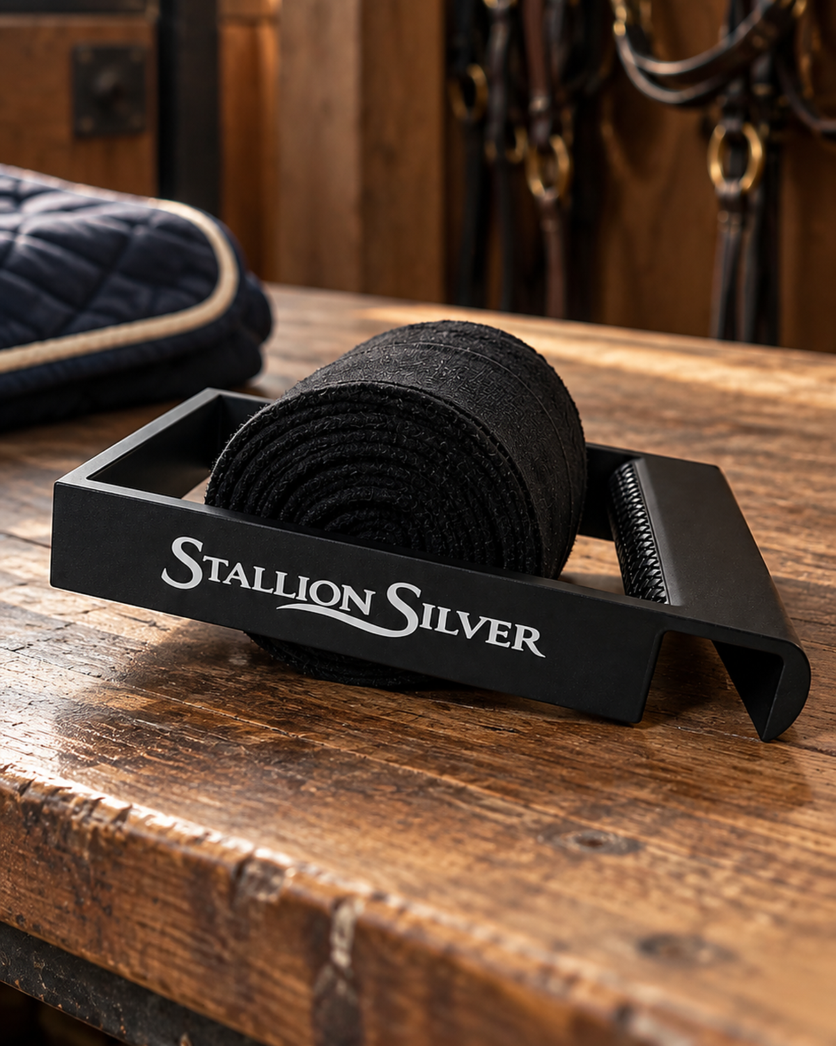 Black Stallion Silver wrap roller with a rolled black wrap on a wooden tack trunk