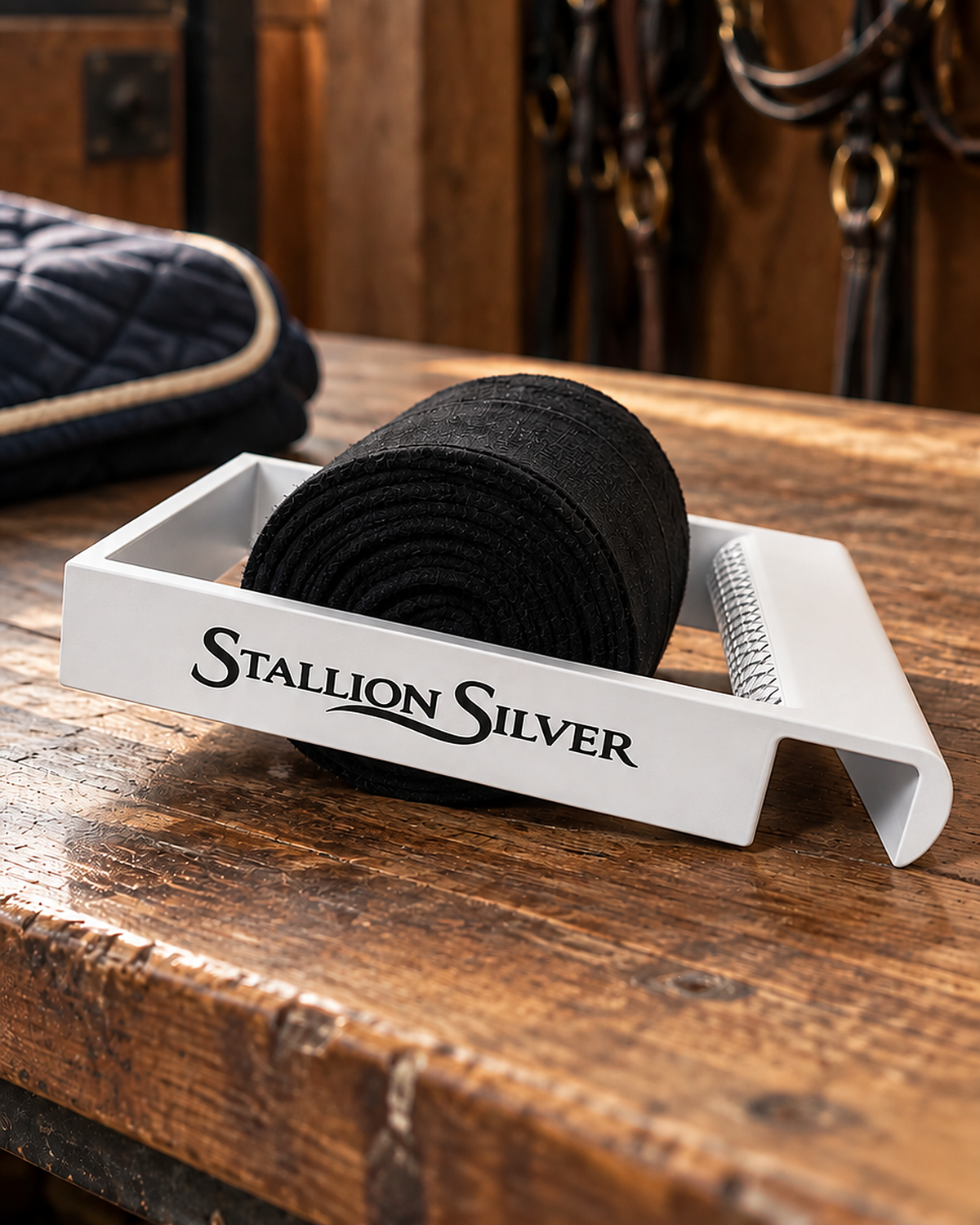 White Stallion Silver wrap roller with a rolled black wrap on a wooden tack trunk